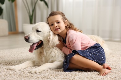 Photo of Little girl with cute dog on carpet at home