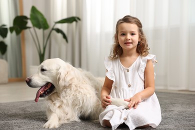 Photo of Little girl with cute dog on carpet at home