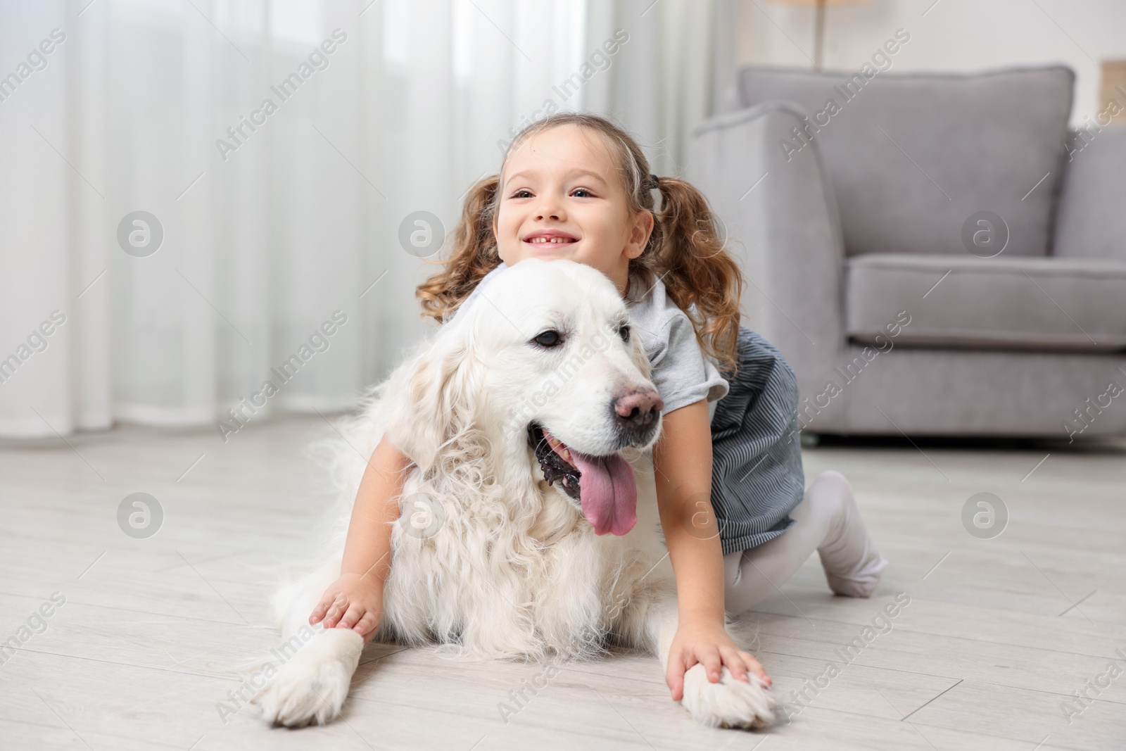 Photo of Little girl with cute dog on floor at home