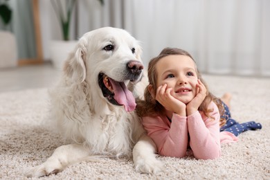 Photo of Little girl with cute dog on carpet at home