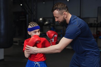 Boxing coach training boy in sport center