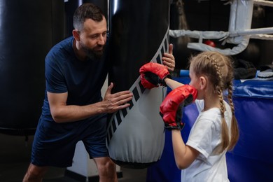 Boxing coach training girl in sport center