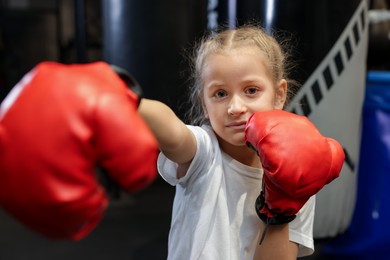 Girl in protective gloves having boxing practice indoors