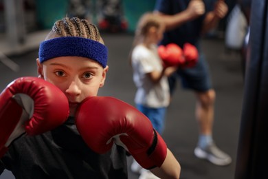 Photo of Boy in protective gloves during boxing practice at training center