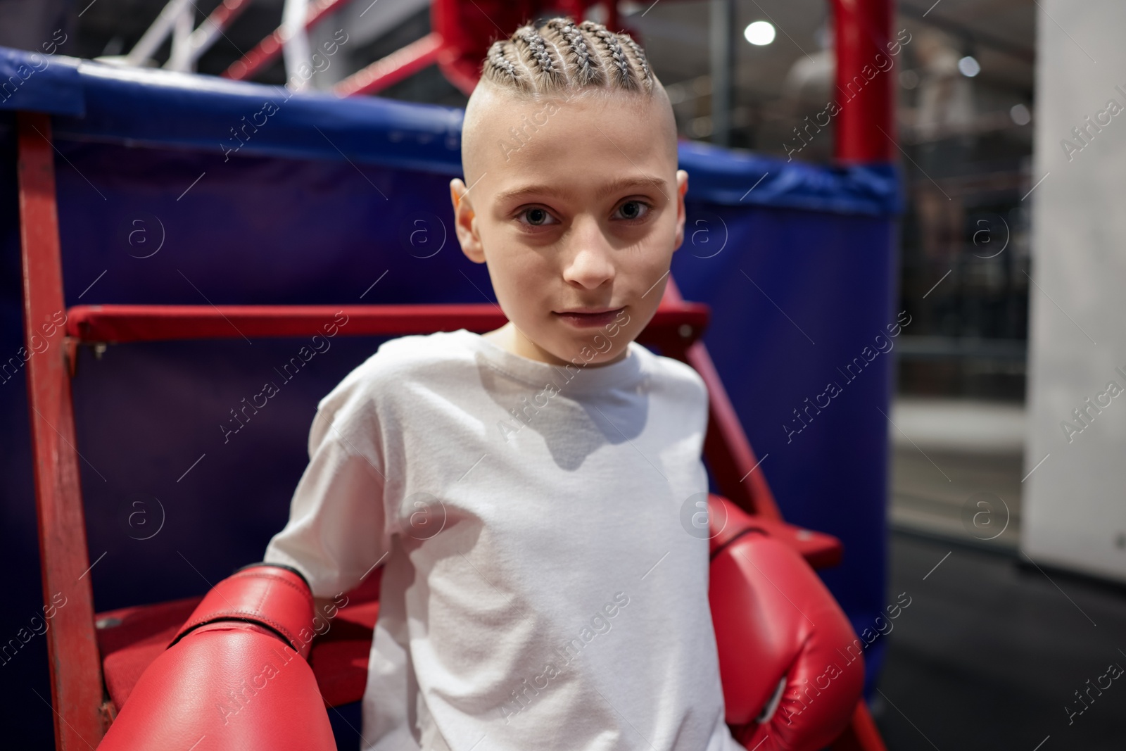 Photo of Boy in protective gloves sitting near boxing ring