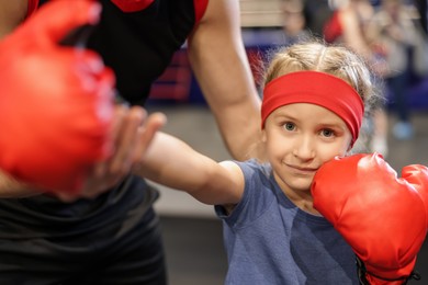 Girl in protective gloves having boxing practice with her coach at training center