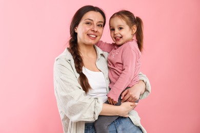 Photo of Portrait of happy mother with her cute daughter on pink background