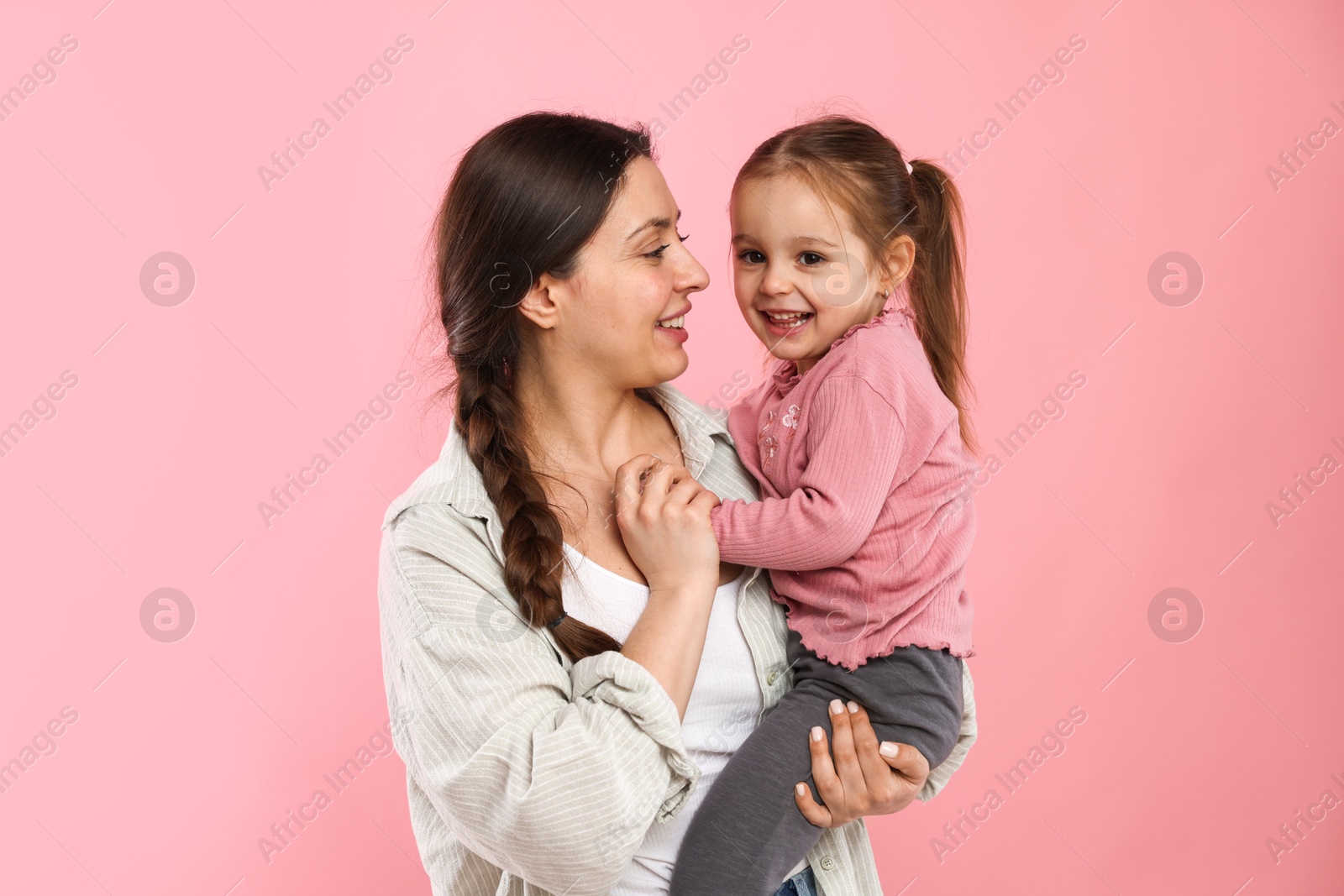 Photo of Portrait of happy mother with her cute daughter on pink background