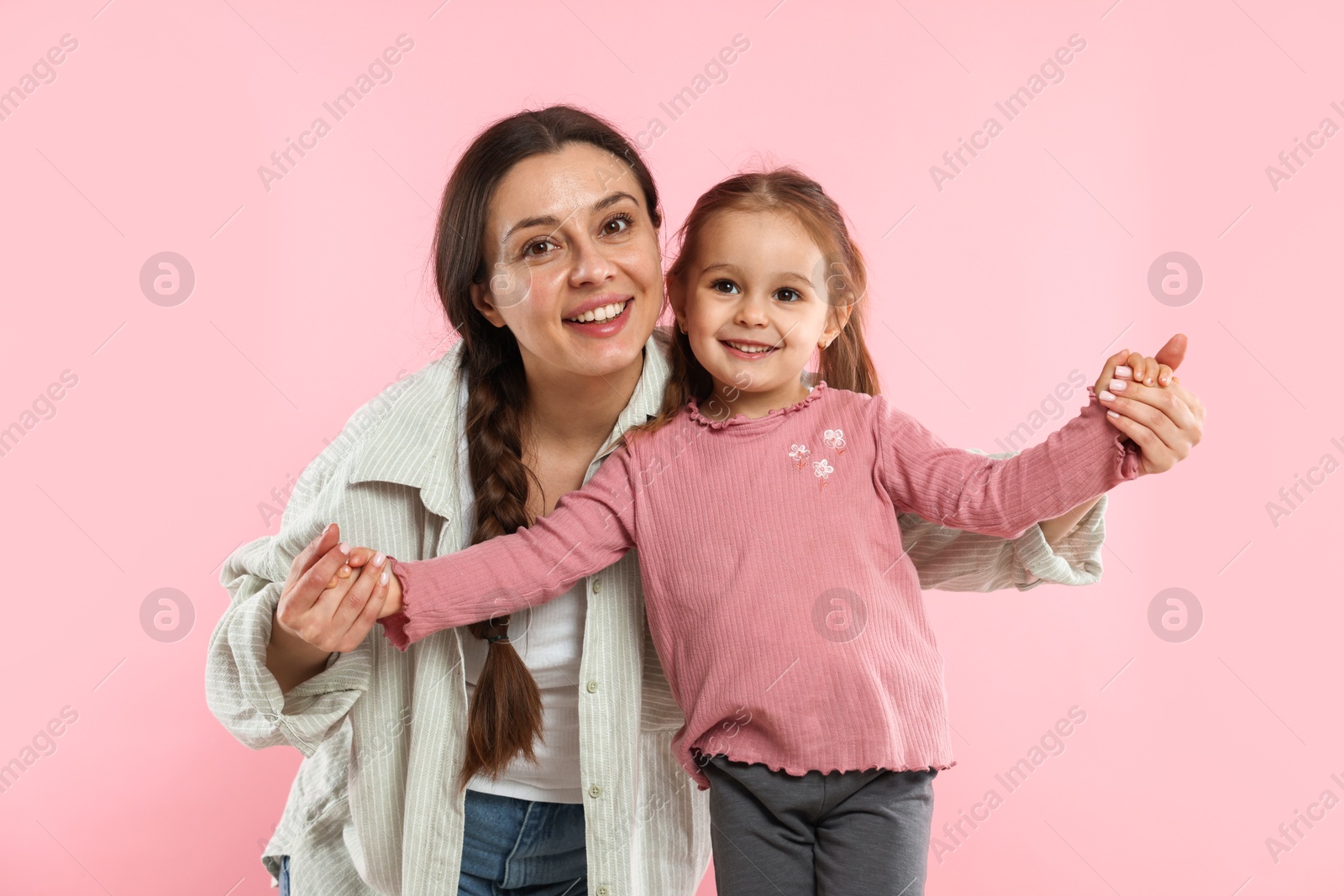 Photo of Family portrait of beautiful mother with little daughter on pink background