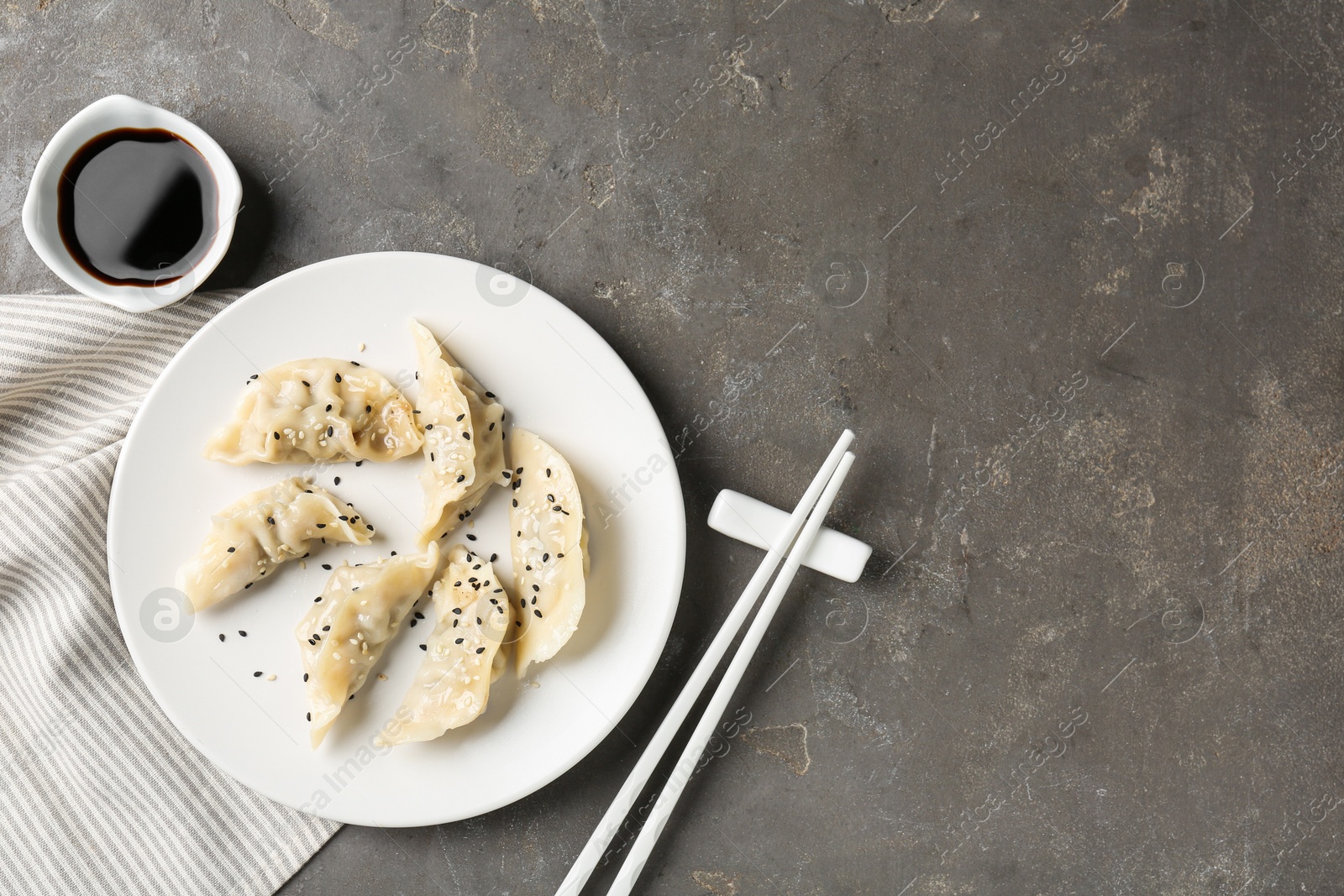 Photo of Delicious gyoza dumplings with sesame seeds served on grey table, top view. Space for text