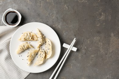 Delicious gyoza dumplings with sesame seeds served on grey table, top view. Space for text