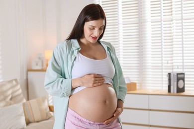 Beautiful pregnant woman with cute belly at home