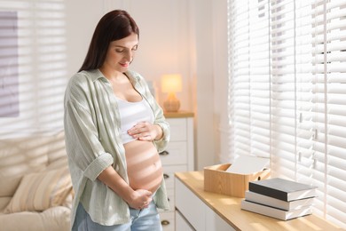 Photo of Beautiful pregnant woman with cute belly near window at home