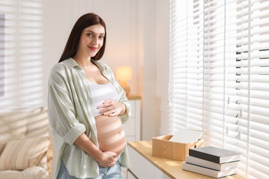 Photo of Beautiful pregnant woman with cute belly near window at home