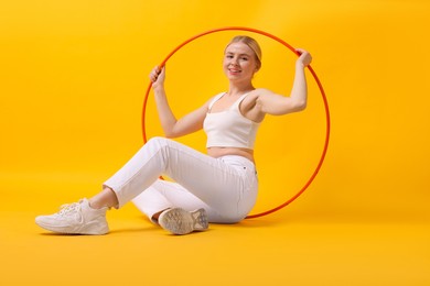 Photo of Beautiful young woman with hula hoop on yellow background