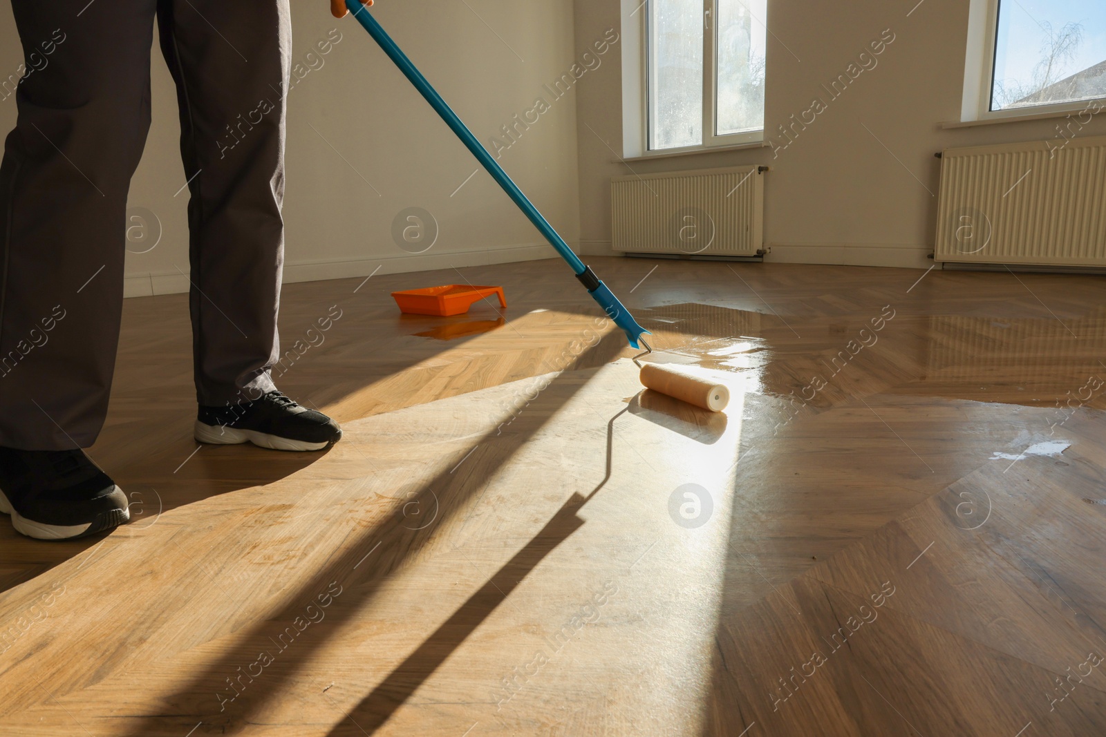 Photo of Man polishing parquet with varnish indoors, closeup