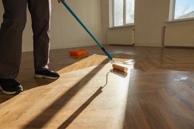 Man polishing parquet with varnish indoors, closeup