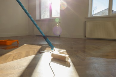 Photo of Polishing parquet with roller and varnish indoors, closeup