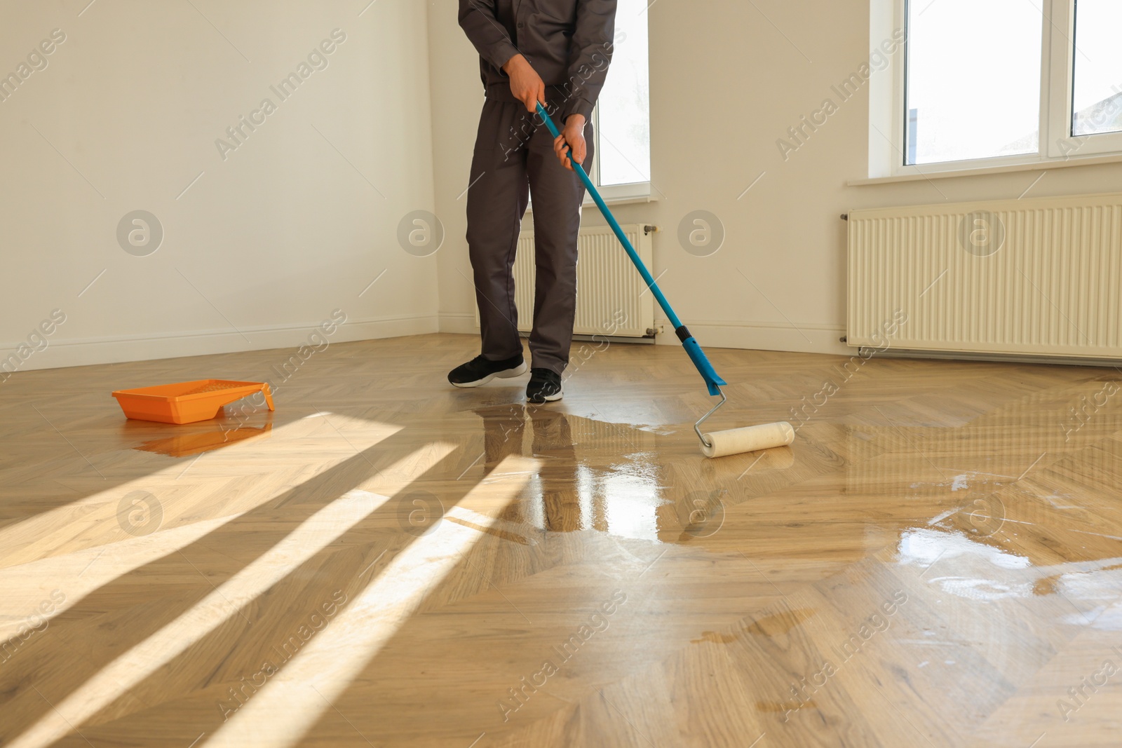 Photo of Man polishing parquet with varnish indoors, closeup