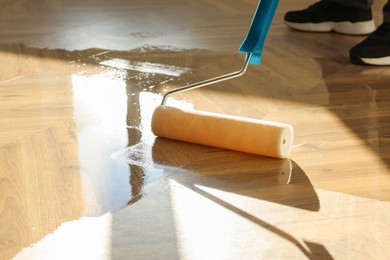 Photo of Man polishing parquet with varnish indoors, closeup. Space for text