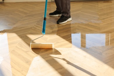 Man polishing parquet with varnish indoors, closeup