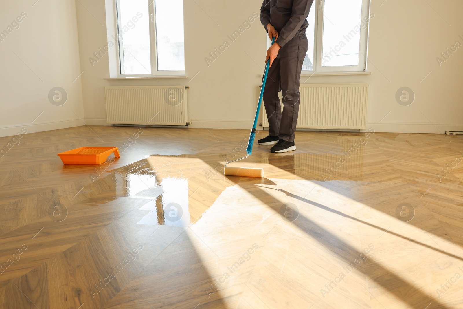 Photo of Man polishing parquet with varnish indoors, closeup