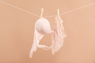 Photo of Beautiful bra and panties hanging on rope against dark beige background