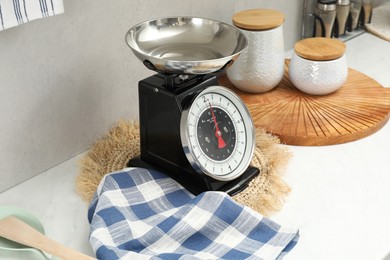 Photo of Retro mechanical kitchen scale and other utensils on white marble countertop indoors