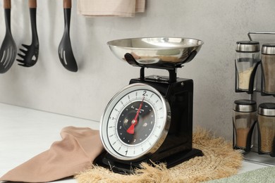 Photo of Retro mechanical kitchen scale and spices on white countertop indoors