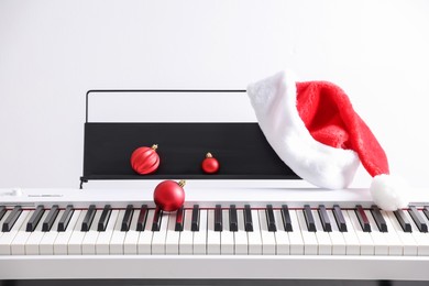 Photo of Christmas ornaments and Santa hat on synthesizer against white background, closeup