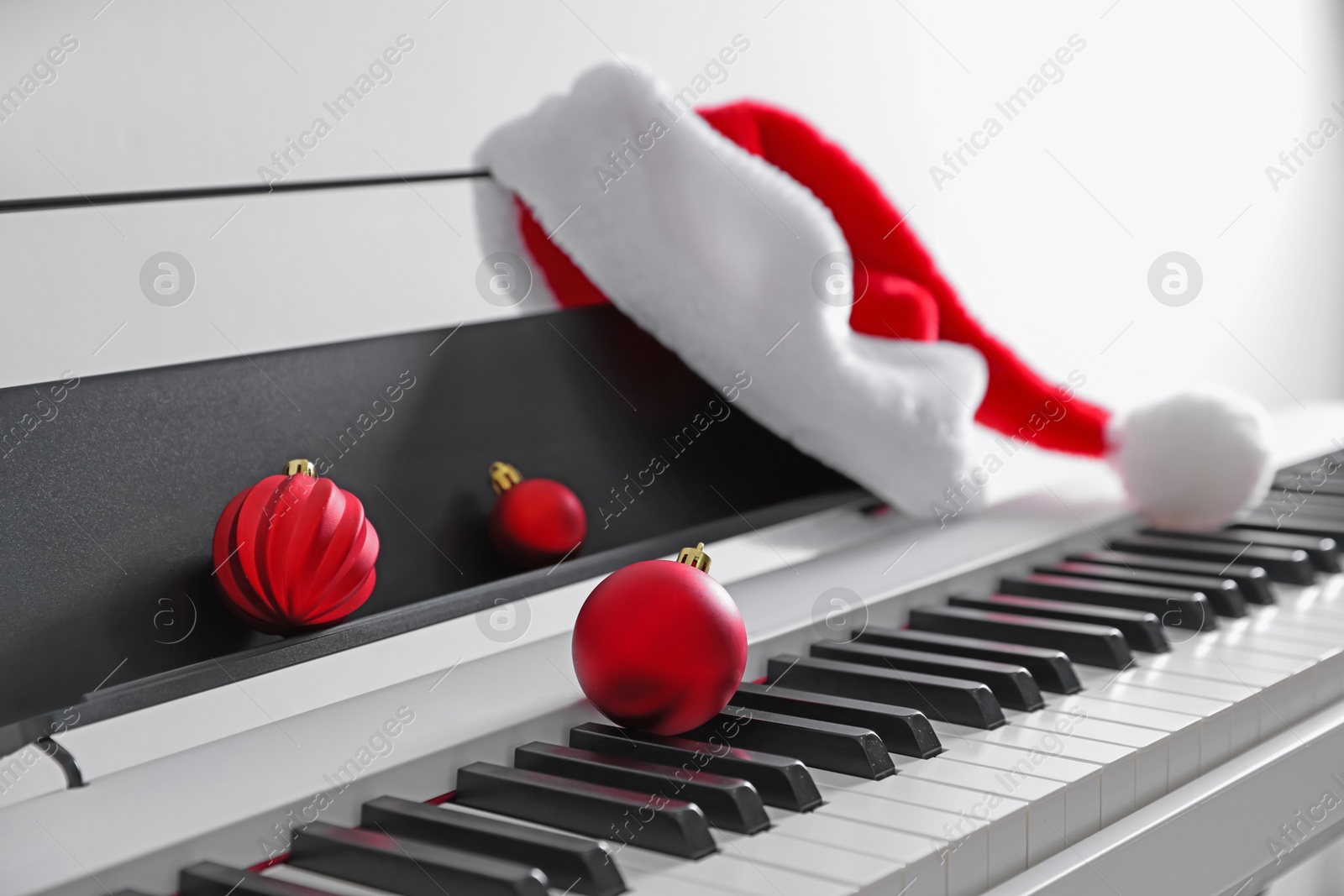 Christmas ornaments and Santa hat on synthesizer against white background, closeup Photo of Christmas ornaments and Santa hat on synthesizer against white background, closeup