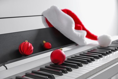 Photo of Christmas ornaments and Santa hat on synthesizer against white background, closeup