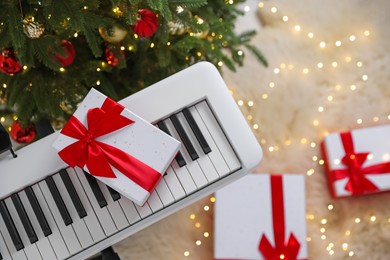 Photo of Synthesizer with gift boxes near Christmas tree indoors, top view