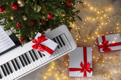 Photo of Synthesizer with gift boxes near Christmas tree indoors, top view