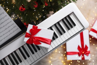 Photo of Synthesizer with gift boxes near Christmas tree indoors, top view