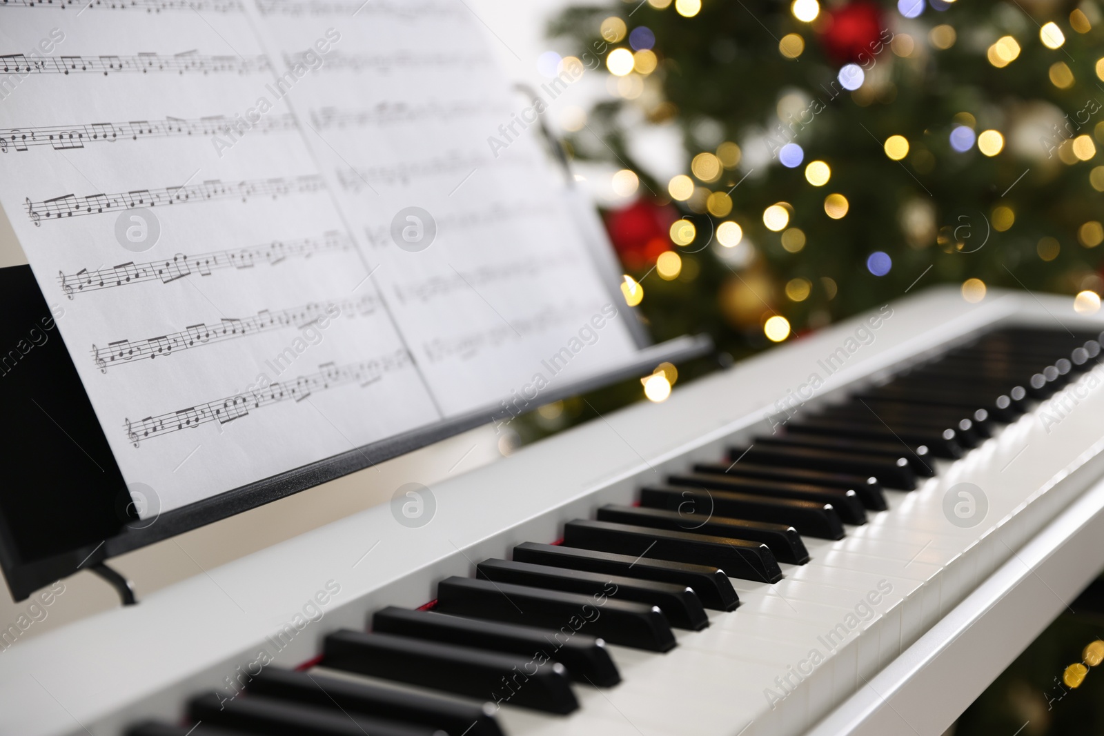Synthesizer with music sheets against blurred Christmas lights, closeup. Bokeh effect Photo of Synthesizer with music sheets against blurred Christmas lights, closeup. Bokeh effect
