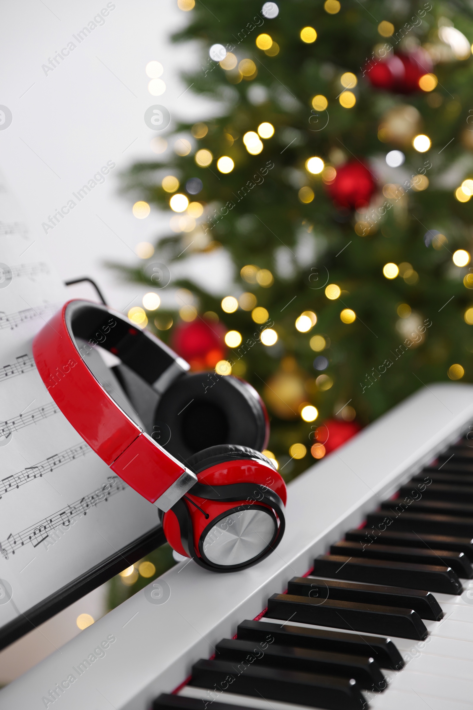 Synthesizer with music sheets and headphones against blurred Christmas lights, closeup. Bokeh effect Photo of Synthesizer with music sheets and headphones against blurred Christmas lights, closeup. Bokeh effect