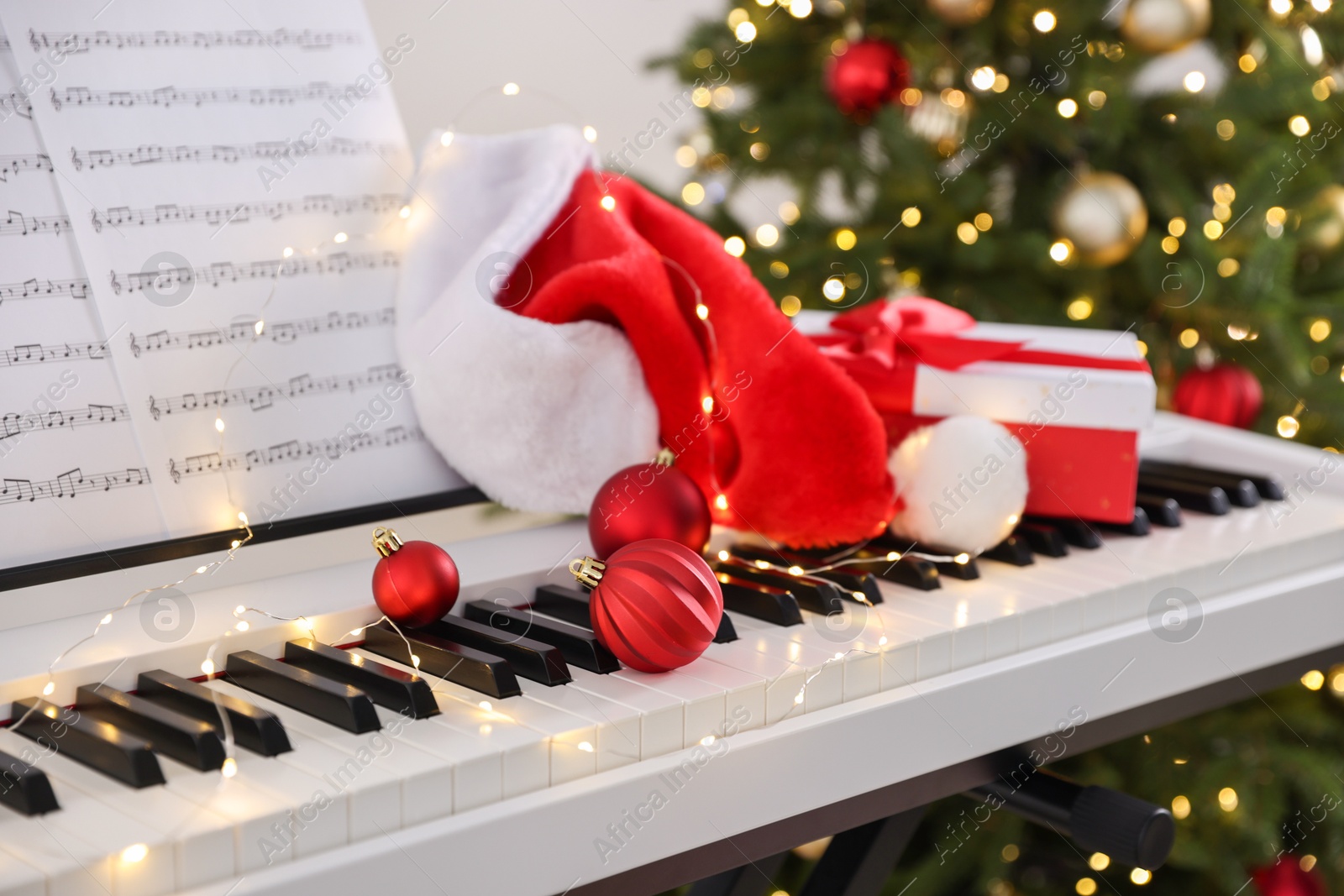 Synthesizer with music sheets and Christmas decor against blurred festive lights, closeup Photo of Synthesizer with music sheets and Christmas decor against blurred festive lights, closeup