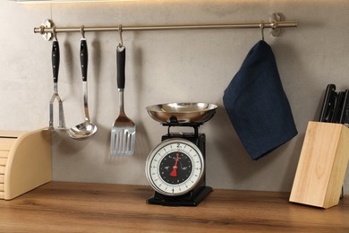 Photo of Retro mechanical kitchen scale on wooden countertop and other utensils indoors