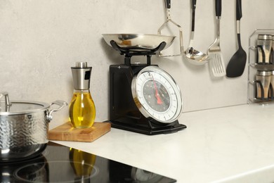 Photo of Retro mechanical kitchen scale on white marble countertop and other utensils indoors