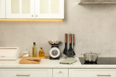 Photo of Retro mechanical kitchen scale and other utensils on white marble countertop indoors