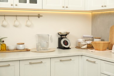 Photo of Retro mechanical kitchen scale, different utensils and food products on white marble countertop indoors