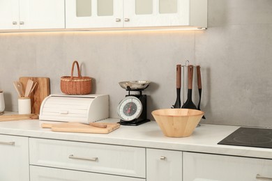 Photo of Retro mechanical kitchen scale and other utensils on white marble countertop indoors