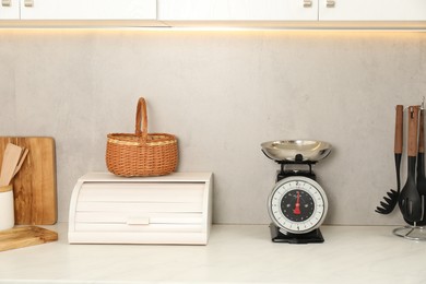 Photo of Retro mechanical kitchen scale and other utensils on white marble countertop indoors