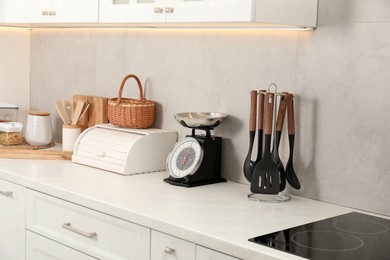 Photo of Retro mechanical kitchen scale and other utensils on white marble countertop indoors