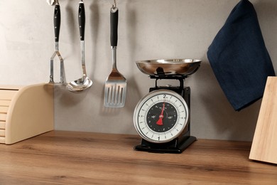 Photo of Retro mechanical kitchen scale on wooden countertop and other utensils indoors