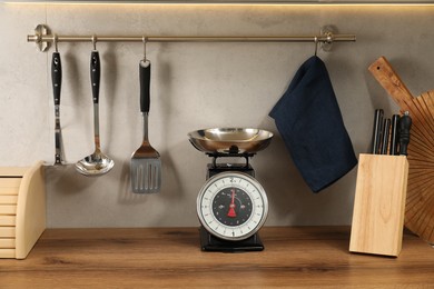 Photo of Retro mechanical kitchen scale on wooden countertop and other utensils indoors