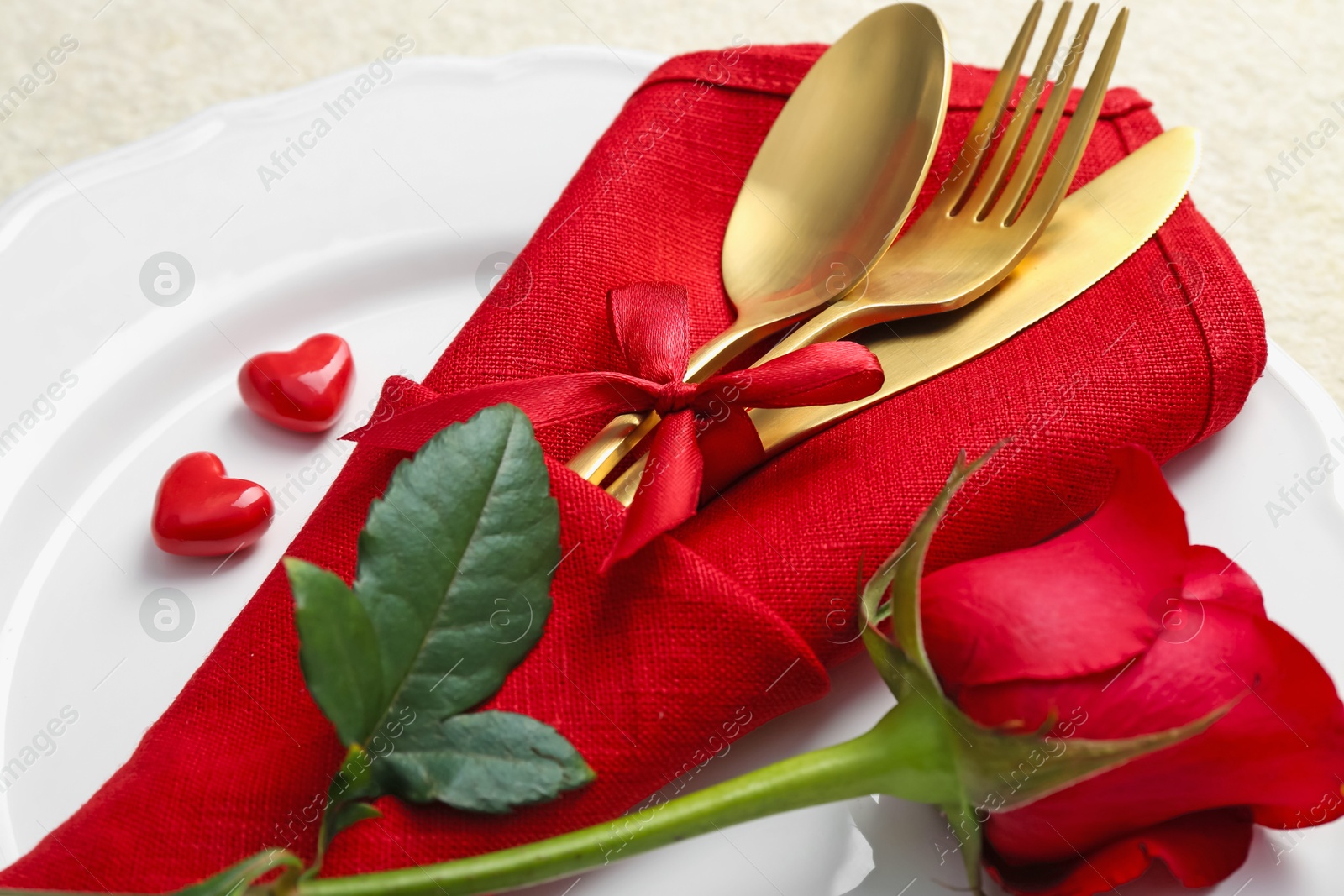 Photo of Romantic place setting with red rose on white table, closeup. Valentine's day celebration