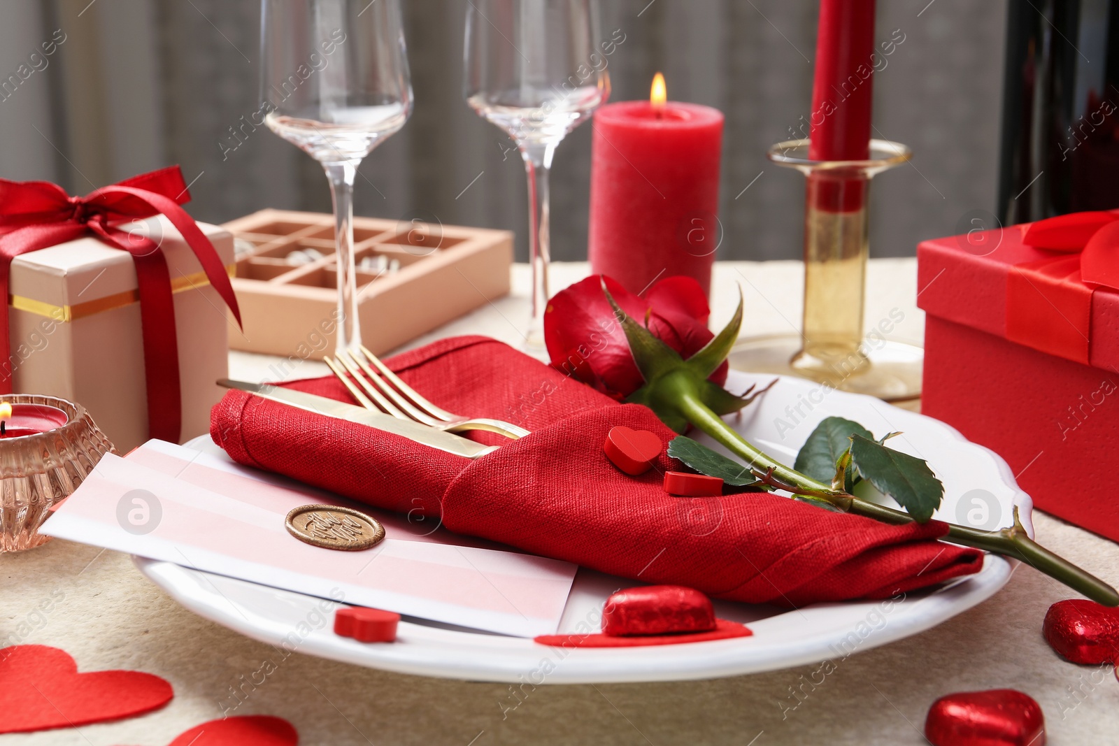 Photo of Romantic place setting with red rose on table, closeup. Valentine's day celebration