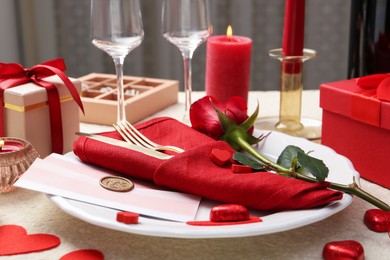 Photo of Romantic place setting with red rose on table, closeup. Valentine's day celebration